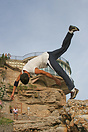 Some local brave teenagers jumping from a very large rock on to the be...