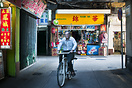 A man riding a bicycle through the streets of Macau.